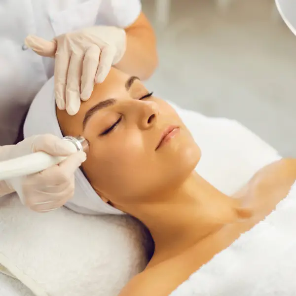 Woman receiving facial skincare treatment at spa.