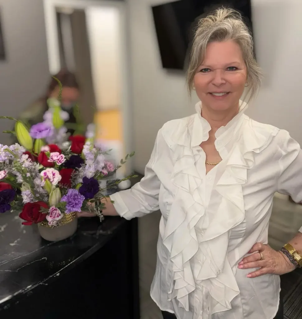 Smiling woman with flowers at reception desk