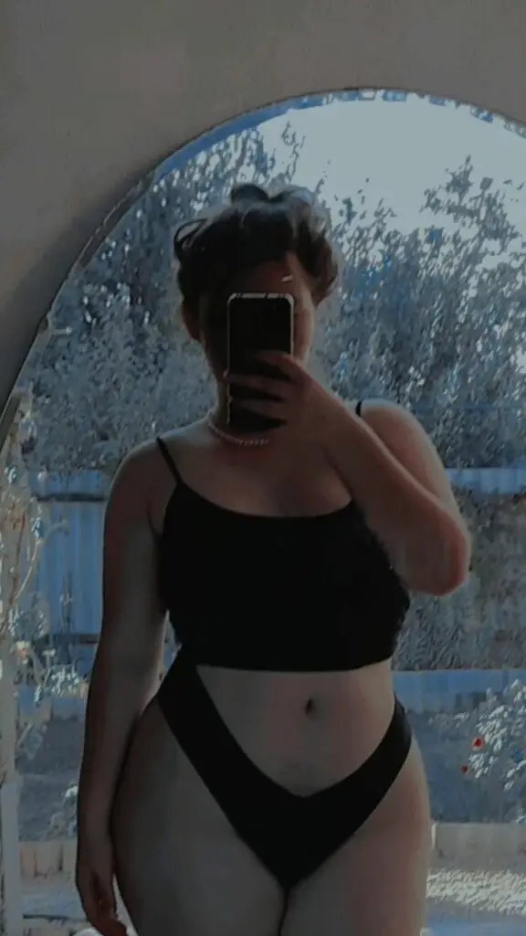 Person in mirror wearing black bikini outside.