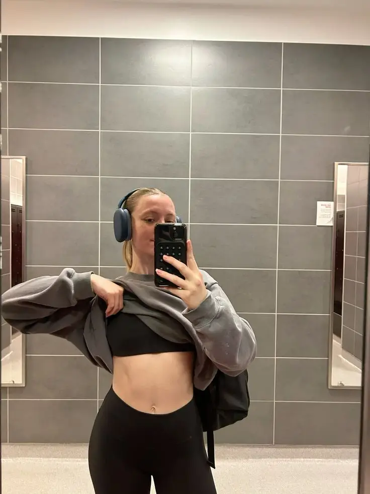 Person in gym attire taking mirror selfie